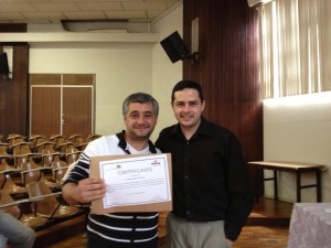 O bolsista e professor da turma de língua inglesa, Allan Cordeiro entrega o certificado para o aluno Eduardo de Oliveira 